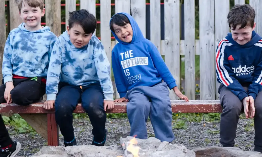 Kids sitting around communal fire pit